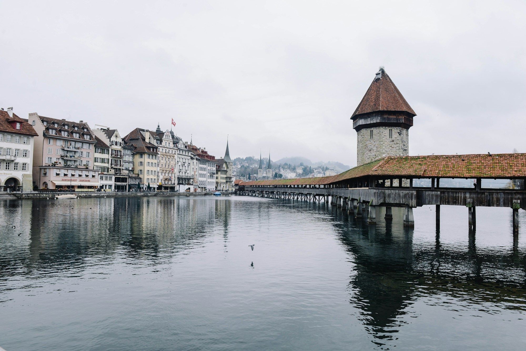 Die Kapellbrücke in Luzern mit Blumenschmuck und der Altstadt im Hintergrund